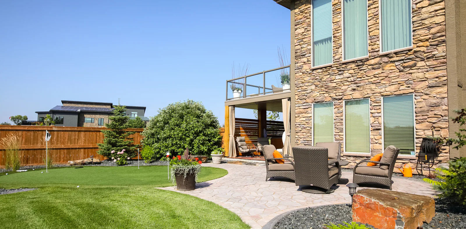 Modern backyard patio with seating and a landscaped lawn
