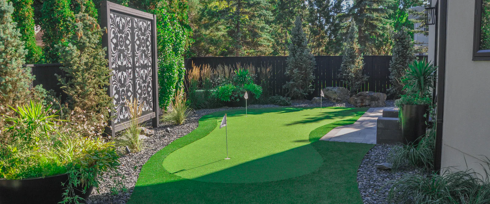 Synthetic turf putting green bordered by a garden bed
