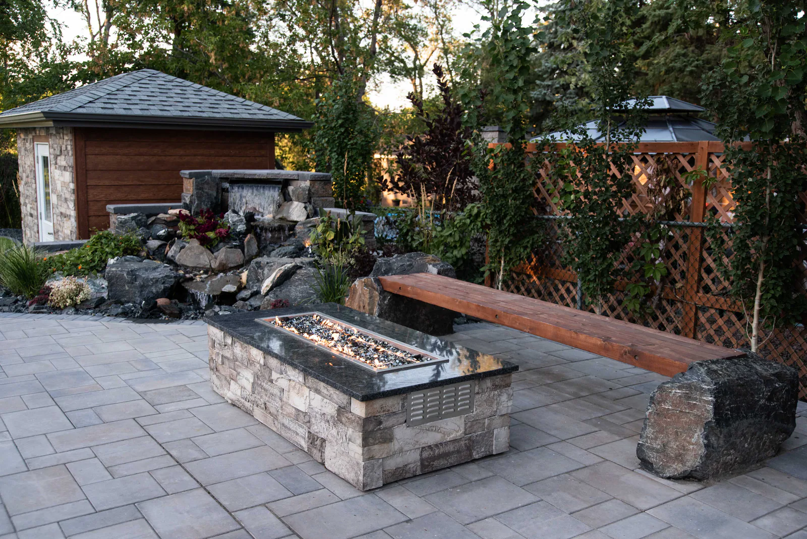 Paver patio with a stone fire table and built-in bench