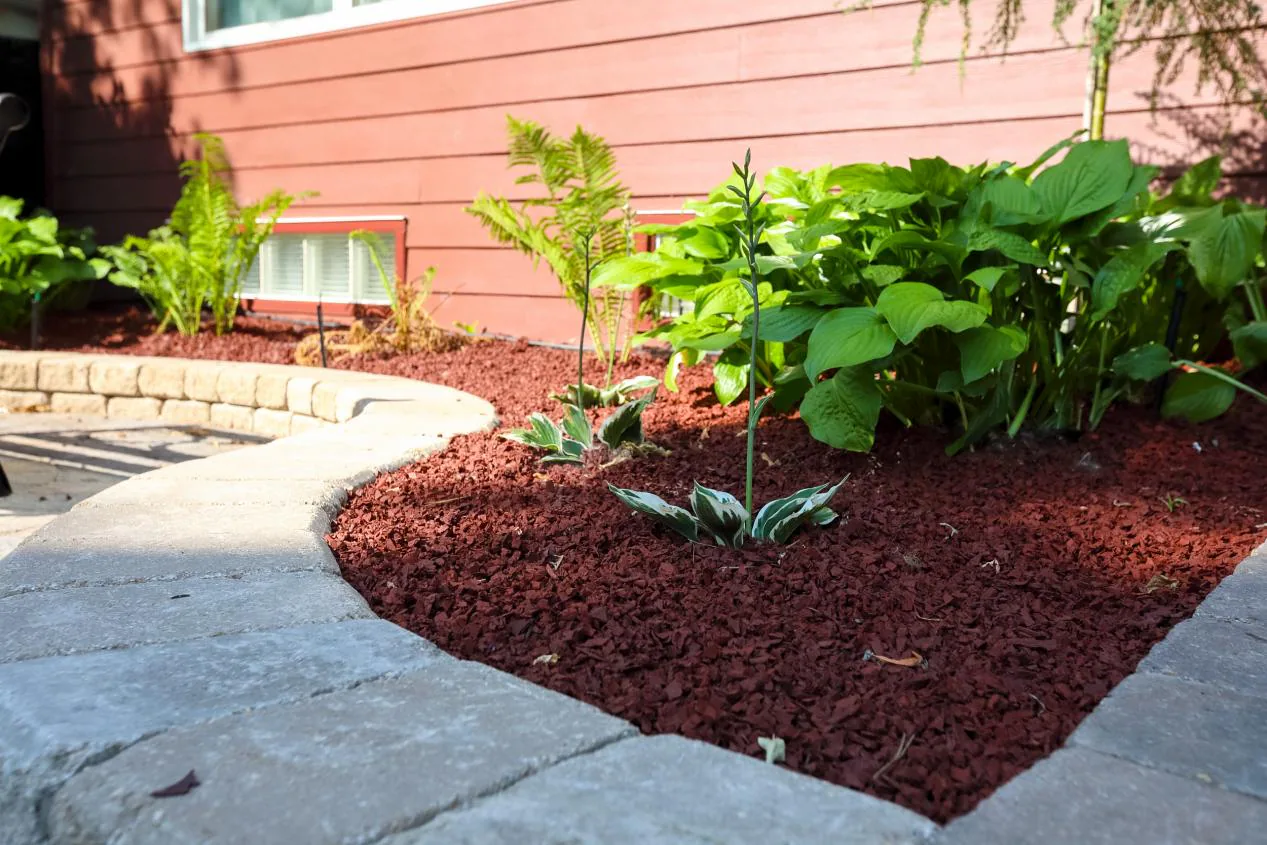 Red wood mulch installed around a landscaped garden bed