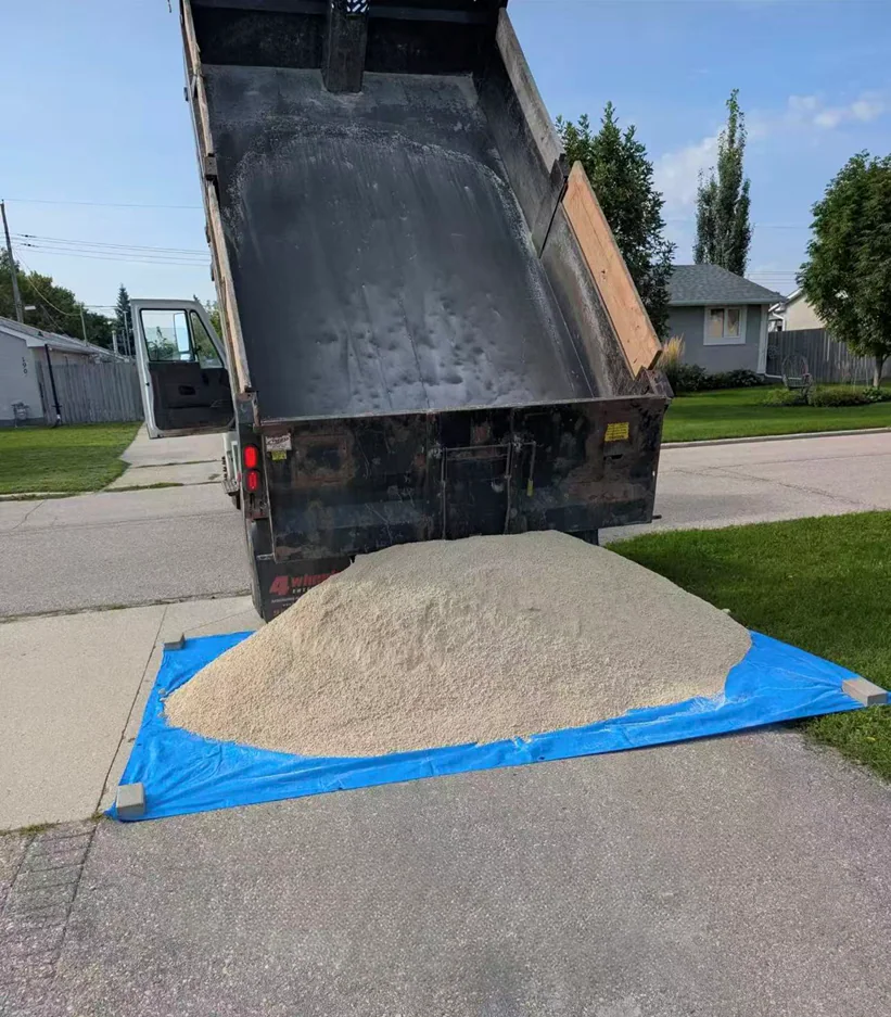 Landscape material delivery truck unloading soil at a Winnipeg property
