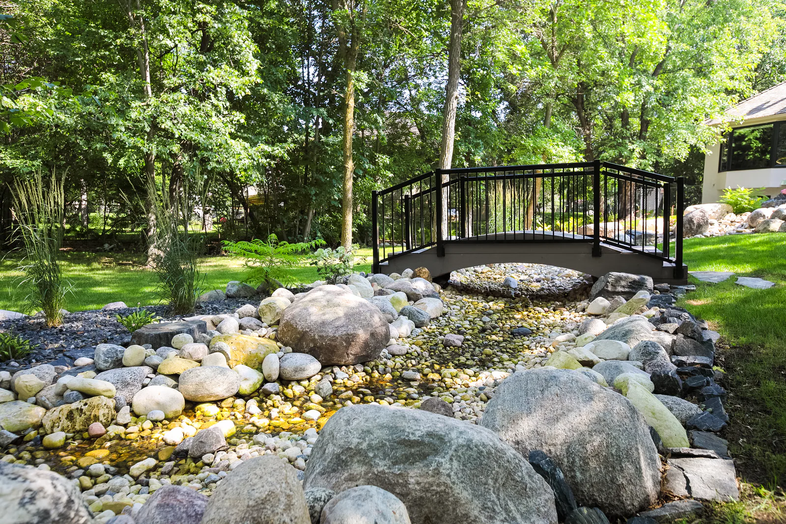 River rock dry creek with a small garden bridge