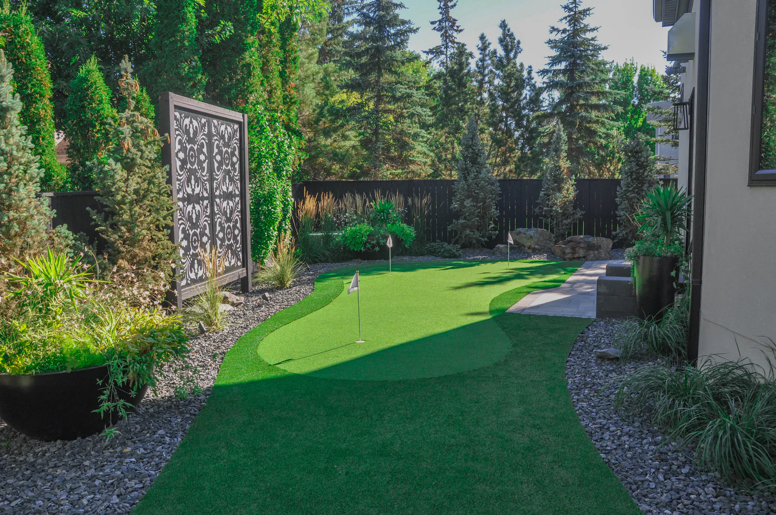 Synthetic turf putting green bordered by a garden bed