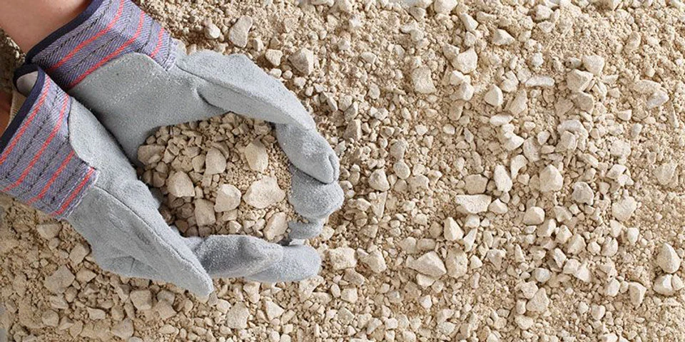 Gloved hand holding crushed limestone aggregate