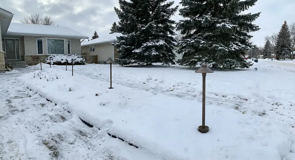 Snow-covered Winnipeg yard with outdoor landscape light fixtures