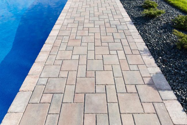 Interlocking concrete pavers installed beside a swimming pool